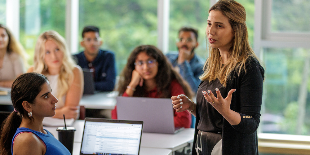An professor gestures while teaching to a class of students