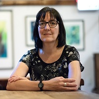 A photo of Dr. Diane Crocker, with her arms resting on a table in front of her.