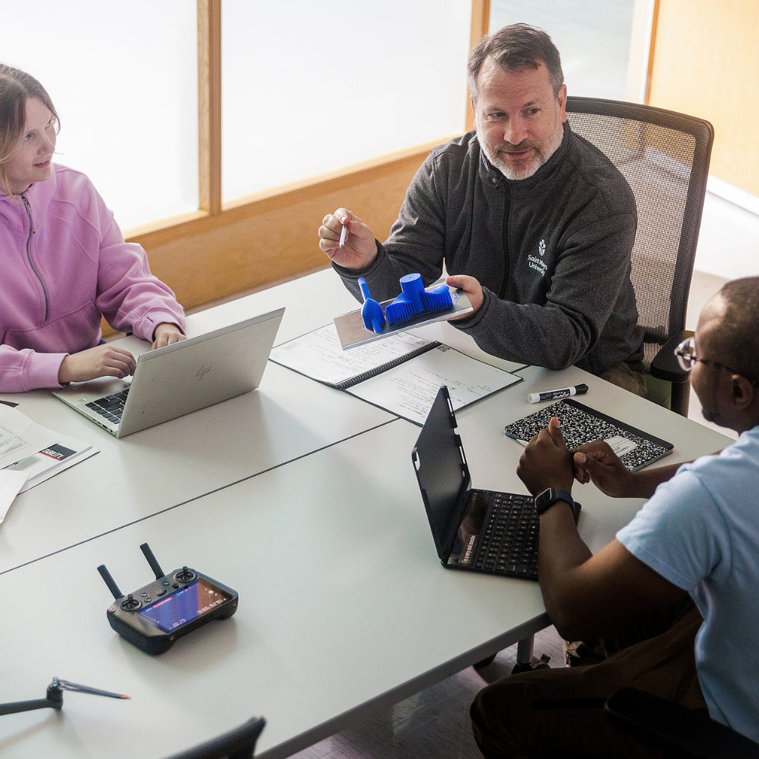A prof chats with students at a table