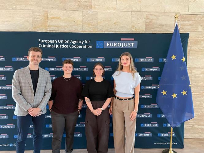 4 SMU POLI students in front of the sign for EUROJust