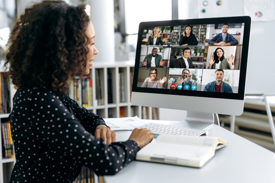 A woman looking a a screen with multiple people in an online meeting