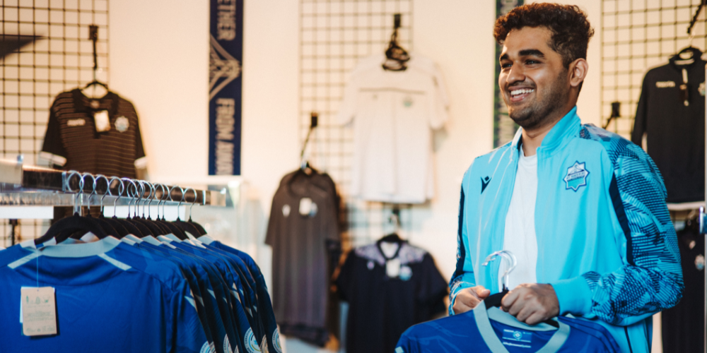 A student hangs jerseys inside a sports merchandise store