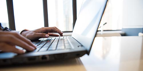 Hands typing on a laptop keyboard.